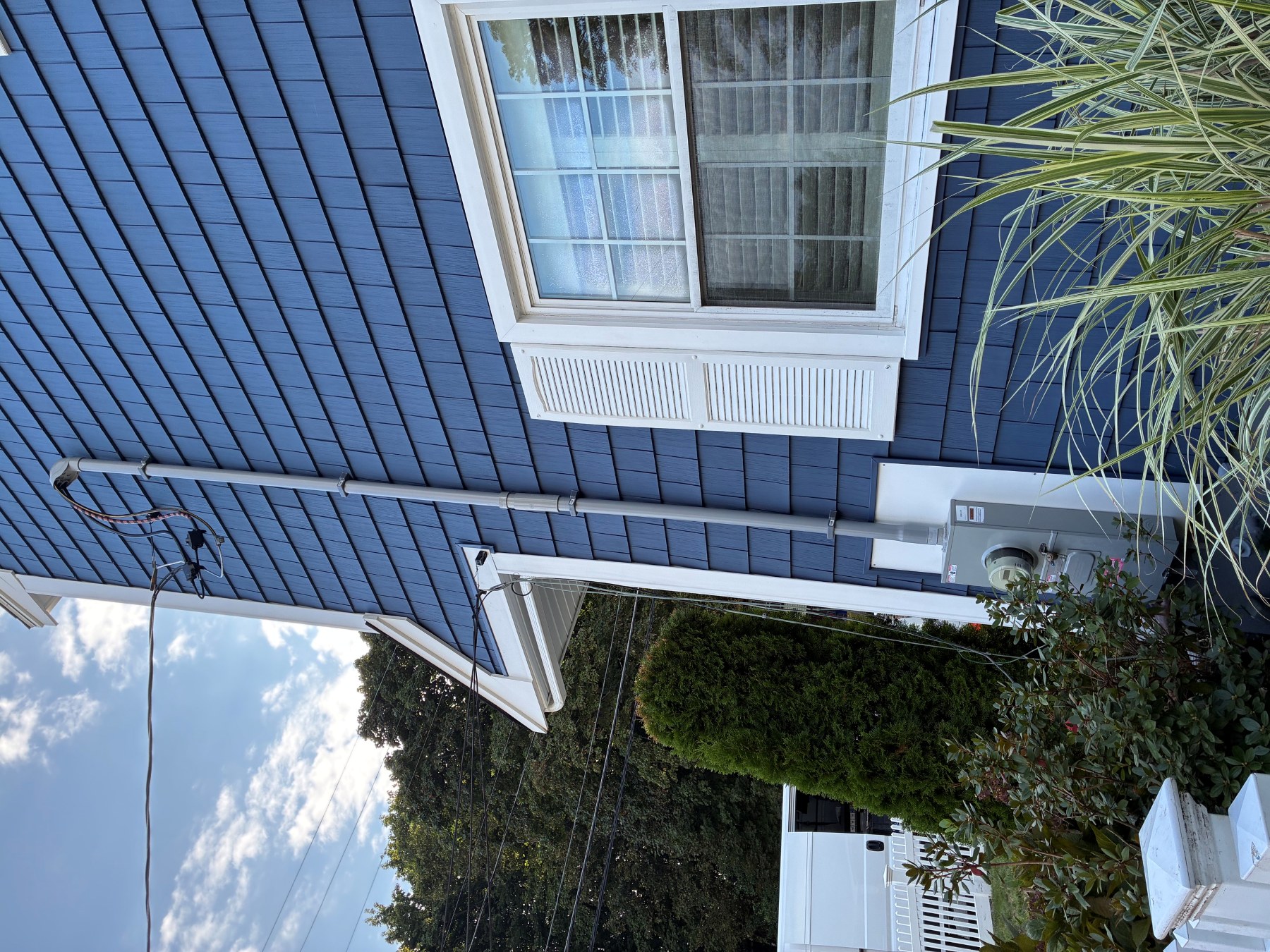 Boston Light & Power electrician installing a new overhead service mast and meter on a shingled home in Cohasset, MA.