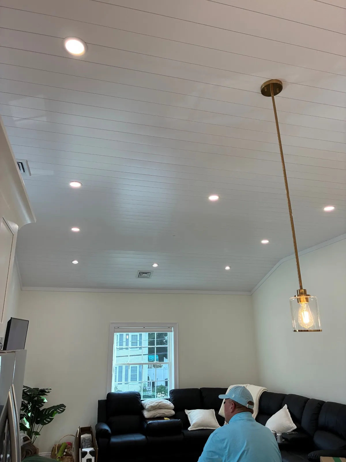 Recessed lighting and a brass pendant on a vaulted living room ceiling