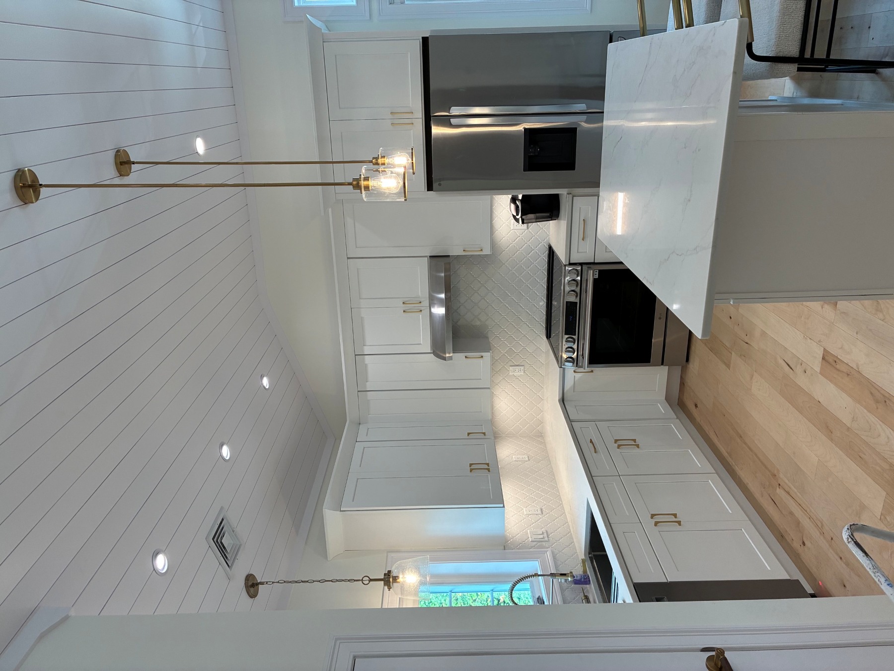 Boston Light & Power electrician installing pendant lights and recessed lighting in a renovated kitchen in Braintree, MA.
