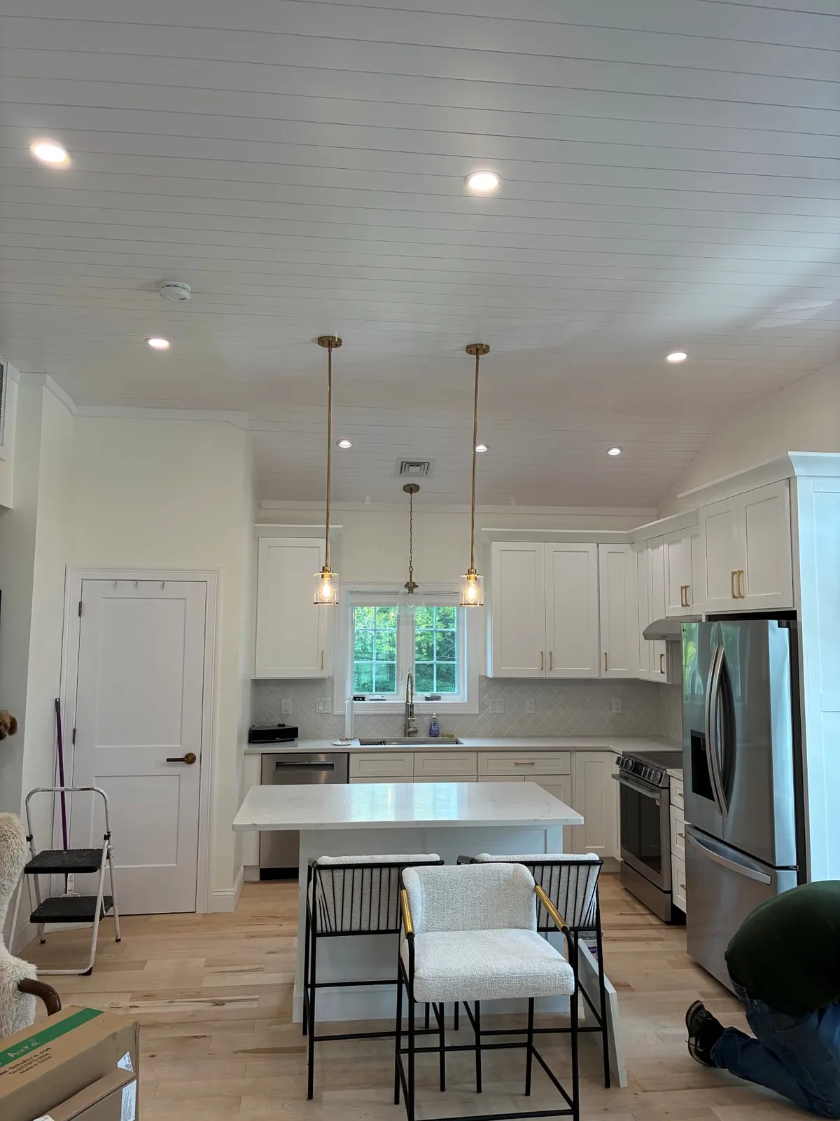 Recessed lighting and island pendants on a vaulted shiplap ceiling