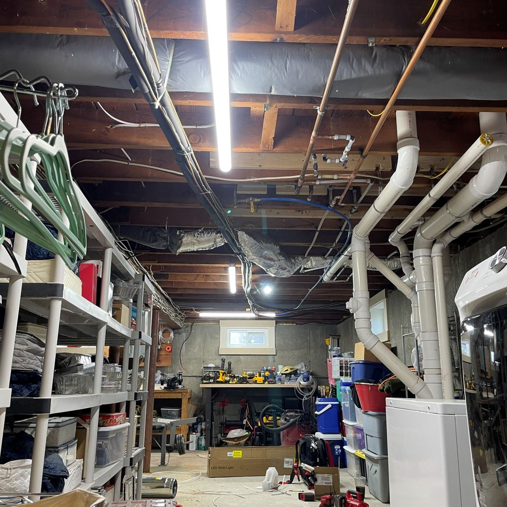 Boston Light & Power electrician installing LED shop lights in a basement in Weymouth, MA.