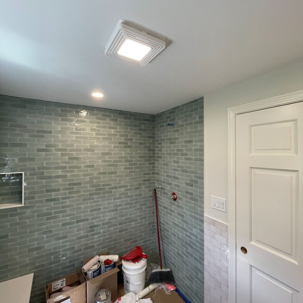 Boston Light & Power electrician installing a bathroom fan and light combination in Milton, MA.