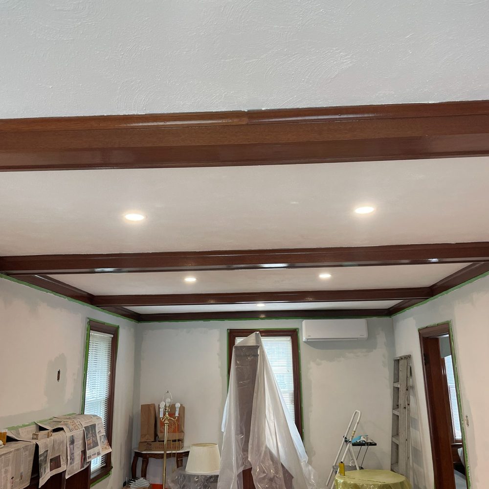 Boston Light & Power electrician wiring recessed lights in a beamed living room in Hingham, MA.