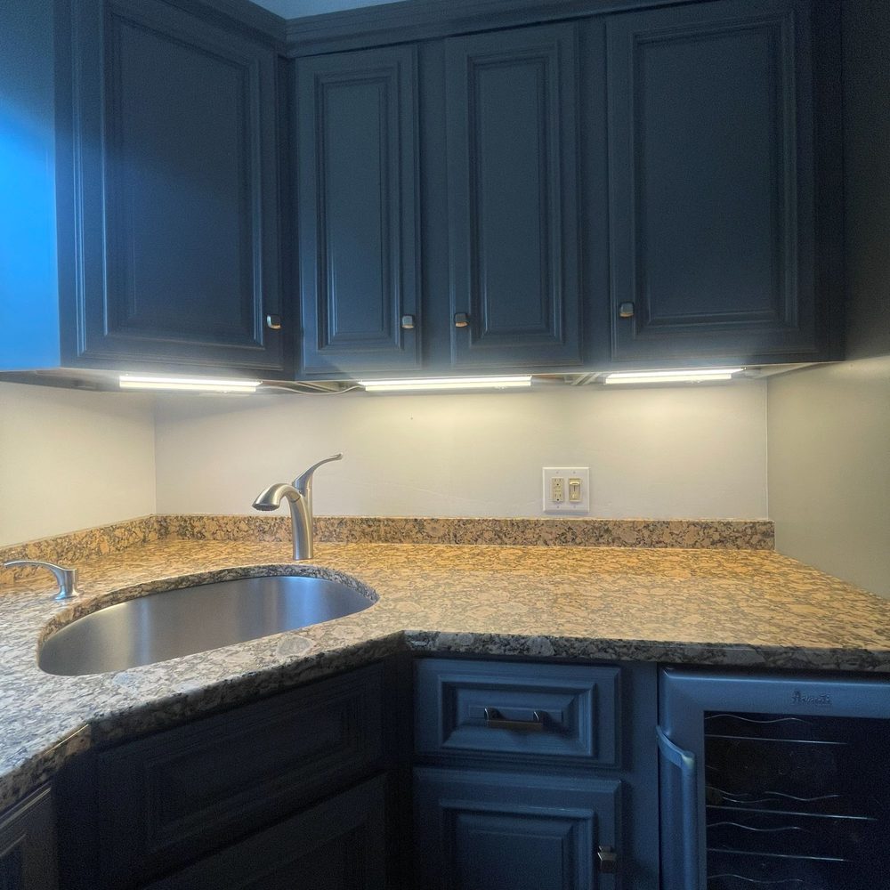 Boston Light & Power electrician installing under-cabinet lighting at a wet bar in Braintree, MA.